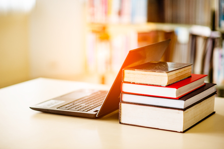 Bookshelves and laptops are placed on the library desk.の写真素材