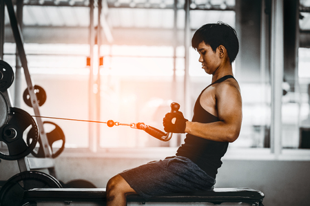 young man making low cable pulley row seated.Concept of healthy lifestyle.  bodybuilder in the gym.の写真素材