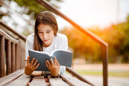 Beautiful young brunette woman lying on the amphitheater with a book in her hands.の写真素材