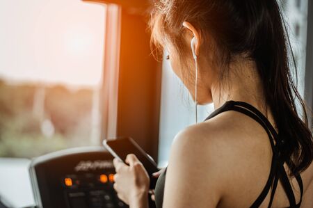 Fitness woman is choosing music to run on a treadmill.exercising concept.fitness and healthy lifestyle.の写真素材