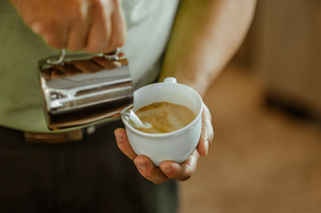 Closeup hands pouring milk and preparing fresh cappuccino,の写真素材