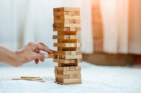 hand  pulling out or placing wood block on the tower in modern office. plan and strategy in business. blur for background.の写真素材