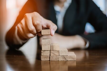 plan and strategy in business.risk concept.hand of man has piling up and stacking a wooden block.Businessman Building The Success.の写真素材