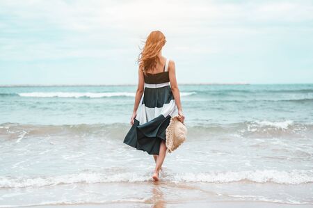 Happy asian women with holding hat walking barefoot to receive the wind and enjoy life on the beach vacation. beach, summer, liftstyle, positive mood, travel, relax concept.の写真素材