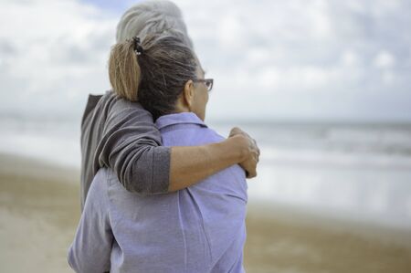 A senior couples embrace the beach in the morning, look at the bright blue skies and plan life insurance with a happy retirement concept.の写真素材