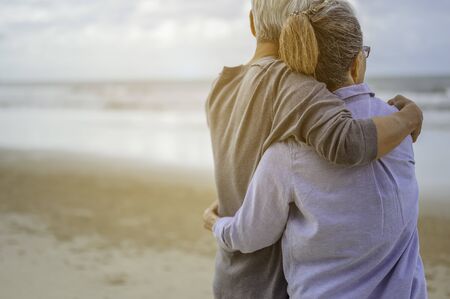 A senior couples embrace the beach in the morning, look at the bright blue skies and plan life insurance with a happy retirement concept.の写真素材