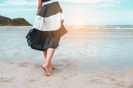 Happy asian women with holding hat stand to receive the wind and enjoy life on the beach vacation. beach, summer, liftstyle, positive mood, travel, relax concept.の写真素材