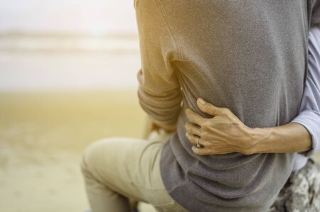 Retirement couple  on a summer evening watch sea, Woman hugging her husband at the beach at sunset.の写真素材