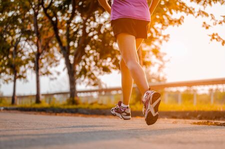 Active healthy runner jogging outdoor. Woman jogging at park in sunrise lightの写真素材