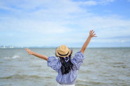 Woman raise her hand up at the beach.の写真素材
