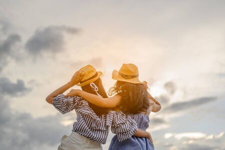 Two woman stay back to camera at  beautiful sunset on the beach.の写真素材