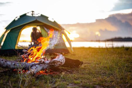 Camping bonfire surrounded by team of asian climbers hiker, they are playing music together in the forest path autumn season. Hiking, hiker, team, forest, camping , activity concept.の写真素材