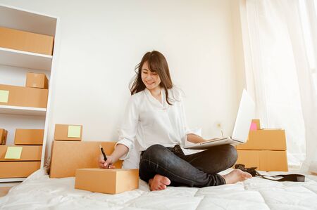 Young woman asian work from home talking with customers to sell products online and delivery for...