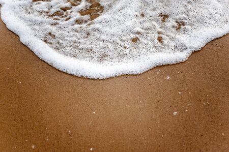 Sea, beach, sand, wave, summer, background concept. White waves on a sandy beach in the summer on sunset. Background sea concept.の写真素材