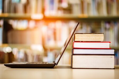 Bookshelves and laptops are placed on the library desk.の写真素材