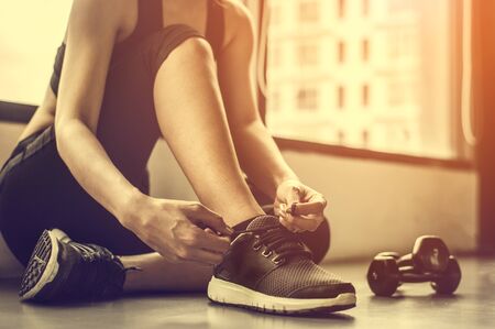  woman tying shoelaces at gym.の写真素材