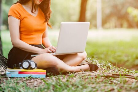 Woman sitting in park on the green grass with laptop.Student studying outdoors. Copy space.の写真素材