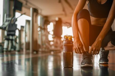 Woman tying shoelaces at gym.young female at gym taking a break from workout.の写真素材