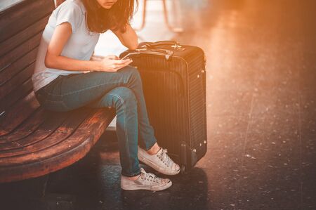 Traveler woman  waits train on railway platform.suitcase in train station. Travelling guy with his luggage while waiting for transport.Copy space.の写真素材