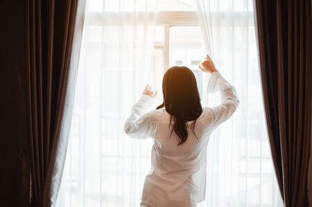 Young woman asia wake up refreshed in the morning and relax in the bedroom on holiday. Asian, asia, relax, alone, technology, lifestyle concept.の写真素材