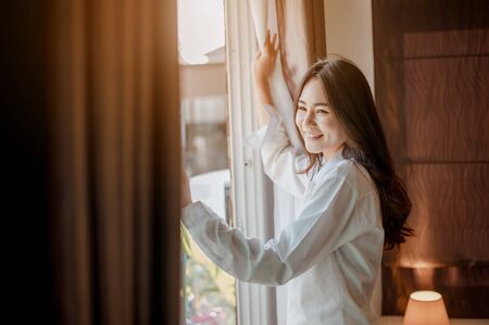 Young woman asia wake up refreshed in the morning and relax in the bedroom on holiday. Asian, asia, relax, alone, technology, lifestyle concept.の写真素材