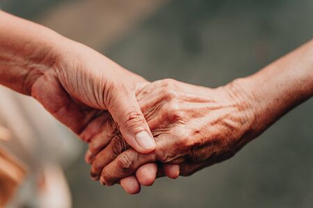 Helping hands elderly , care for the elderly concept.Old and young holding hands on light background.の写真素材