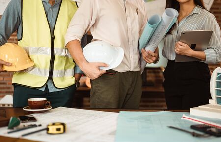 Team of architect are holding on blueprint and helmet working engineering or architecture project at office. Engineer, Engineering, Architecture, Blueprint, Planning, Occupation concept.の写真素材