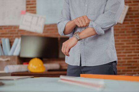 Male architect in formalwear bending working engineering with engineering equipment, blueprint and helmet in office. Engineer, Engineering, Architecture, Blueprint, Planning, Occupation concept.の写真素材
