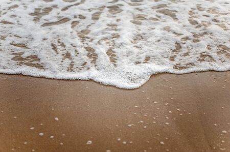 Sea, beach, sand, wave, summer, background concept. White waves on a sandy beach in the summer on sunset. Background sea concept.の写真素材