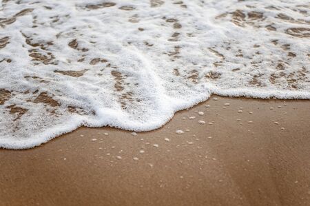 Sea, beach, sand, wave, summer, background concept. White waves on a sandy beach in the summer on sunset. Background sea concept.の写真素材