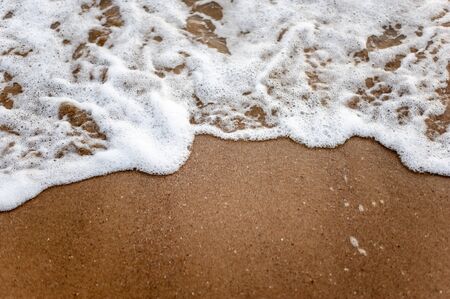 Sea, beach, sand, wave, summer, background concept. White waves on a sandy beach in the summer on sunset. Background sea concept.の写真素材