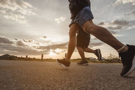 fitness, workout, jogging, exercise, lifestyle and healthy concept. The man is jogging to exercise for his health on the edge of the roadside the sunset.の写真素材