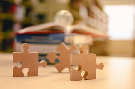 Businessman hands connecting jigsaw puzzle in the library background blur, Success and strategy concept.の写真素材