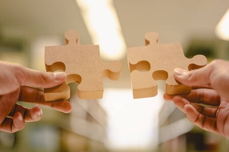 Businessman hands connecting jigsaw puzzle in the library background blur, Success and strategy concept.の写真素材