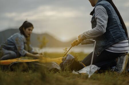 Two women pitching tents for camping On Camping Holiday.の写真素材