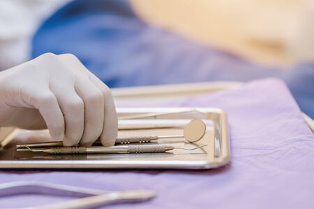 The dentist is picking a dentist's tool to treat the patient's teeth. For beautiful and healthy teethの写真素材