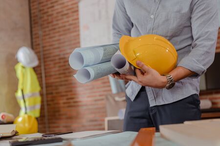 Male architect are holding on blueprint and helmet working engineering or architecture project to come out completely. Engineer, Engineering, Architecture, Blueprint, Planning, Occupation concept.の写真素材