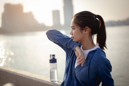 Young woman wipes sweat after a morning workout in the city. A city that lives healthy in the capital Rear view of the city Exercise, fitness, jogging, running, lifestyle, healthy concept.の写真素材