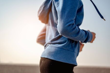 Close-up of body young woman jogging in morning workout at the city. A city that lives healthy in...