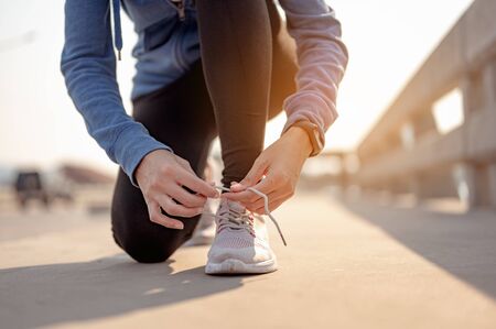 Young women using their hands to tie their shoes jogging in morning workout at the city. A city that lives healthy in the capital. Exercise, fitness, jogging, running, lifestyle, healthy concept.
の写真素材
