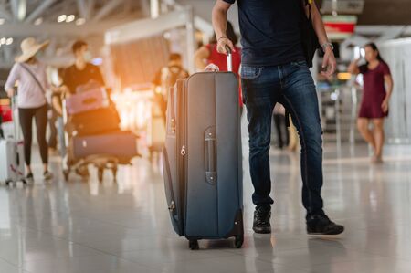 Travelers are walking to drag luggage in modern airport terminal to travel to new places. Rear view. Copy space. Luggage, traveler, travel, airport, walking, holiday concept.の写真素材