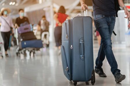 Travelers are walking to drag luggage in modern airport terminal to travel to new places. Rear view. Copy space. Luggage, traveler, travel, airport, walking, holiday concept.の写真素材