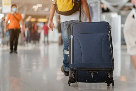 Travelers are walking to drag luggage in modern airport terminal to travel to new places. Rear view. Copy space. Luggage, traveler, travel, airport, walking, holiday concept.の写真素材