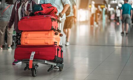 Travelers are walking to drag luggage in modern airport terminal to travel to new places. Rear view. Copy space. Luggage, traveler, travel, airport, walking, holiday concept.の写真素材
