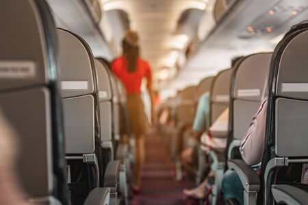 Aisle With an air hostess walking to check the order of passengers before take-off. Airplane, Travel, Smartphone, Airport, ticket, technology concept.の写真素材