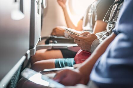 The tourists who are playing the phone and have a ticket on hand on the plane that is preparing to take-off. Airplane, Travel, Smartphone, Airport, ticket, technology concept.の写真素材