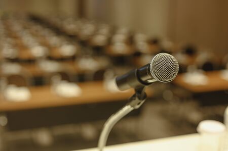 Close up of microphone on stage in meeting room. Blurred background. Microphone, stage, room, class, meeting, greeting concept.の写真素材