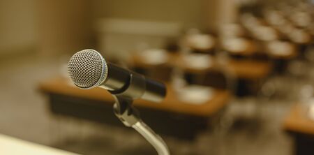 Close up of microphone on stage in meeting room. Blurred background. Microphone, stage, room, class, meeting, greeting concept.の写真素材