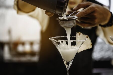 The bartender opens a bottle of red wine using a wine opener. To pour a lot of empty glasses at the bar counter. Blurred background. wine, tasting, open, beverage, bartender, dinner concept.の写真素材
