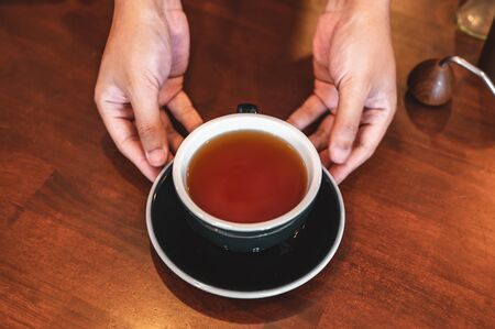 Close up of hands barista man serving coffee in coffee shop. male hands placing a cup of coffee on table. Coffee, Barista, extraction, serve, cafe, lifestyle concept.の写真素材